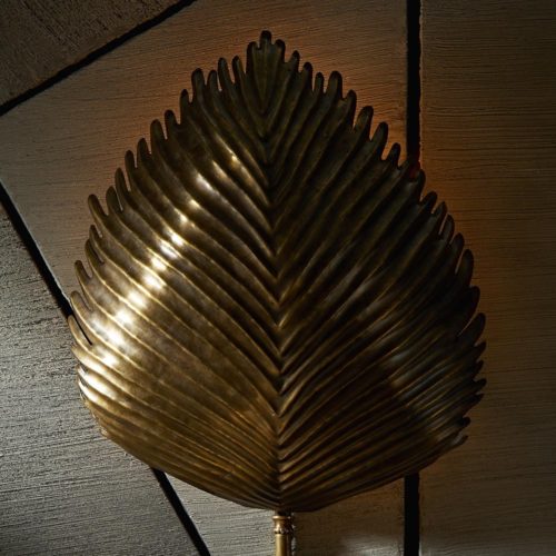 Pressed into the shape of a wild exotic leaf, this sconce is truly unique in all of its handcrafted features. Organic textures are made by pressing the plate of brass into shape, then the use of special tools and immense skill are needed to get the ridges and lines just right