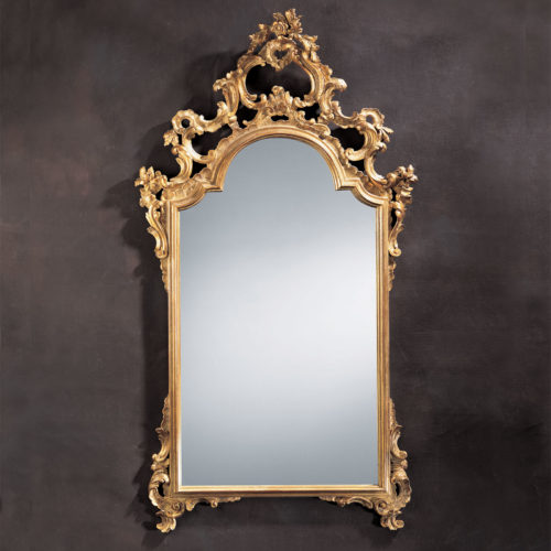 This elegant carved wood mirror is hand crafted in 18th century Italian style. Decorative wall mirror has floral design with graceful scrolls. Mirror has an antiqued gold leaf finish. This mirror is hand-crafted in Italy