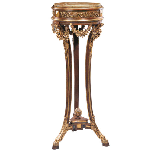 Elaborate hand crafted in Regency style carved wood pedestal. Regency pedestal richly embellished with carved in deep relief floral swags and stylized rising scrolled leafs. Pedestal has round Valencia marble top and graced with elegant scroll motif border. Carved wood pedestal finished in antiqued satinwood and has a hand applied gold metal leaf accents