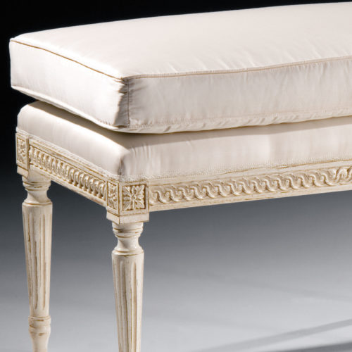 Louis XVI style carved wood bench with antique white finish. Bench has loose cushion and off-white upholstery. This bench is hand-crafted in Italy