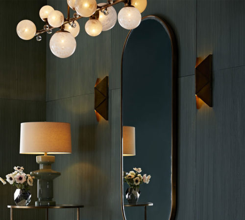 modern interior with brass wall sconces. Modern origami takes shape in this two-light wall sconce. The sharp angles of the iron form work to filter light through the top and bottom, allowing the light to play on the symmetry of its geometric design. Its antique brass finish helps to warm up a wall space