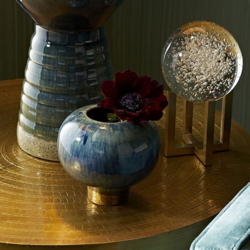 modern decorative accents featuring peacock colors, deep velvet peacock sofa with peacock and bronze vases. Accents atop an elegant gold table.