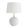 An exaggerated antique brass stem reveals an oversized white orb foundation composed of rice stone.A functional art piece in its simplest form for traditional and modern settings. Topped with an ivory microfiber drum shade with ivory cotton lining and a 1
