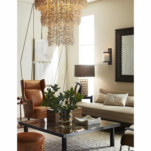 Unique and transitional living room with mixed materials and elements. Upholstered cream sofa with dark iron mirror and table. Mixed materials with the leather wing armchair and beaded shell chandelier.