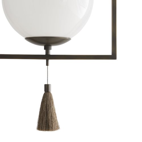 Orb and Tassel Pendant emulates a sleek steel trapeze finding equilibrium with its glowing glass orb. A fine-threaded tassel hangs from the center of the aged bronze fixture. She betrays the family secret of balance and elegant form. Finished in aged bronze
