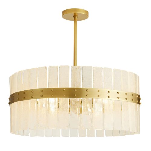 This timeless chandelier has a beauty all its own. Constructed of over twenty panels of organic seeded glass, each is formed by hand, so they will feature their own individual forms and naturaledges. The outer steel band shines in an antique brass finish, with rivet details that offer an unexpected edge to the refined aesthetic